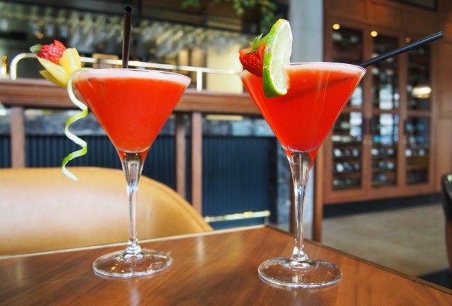 Two red cocktails with fruit.
