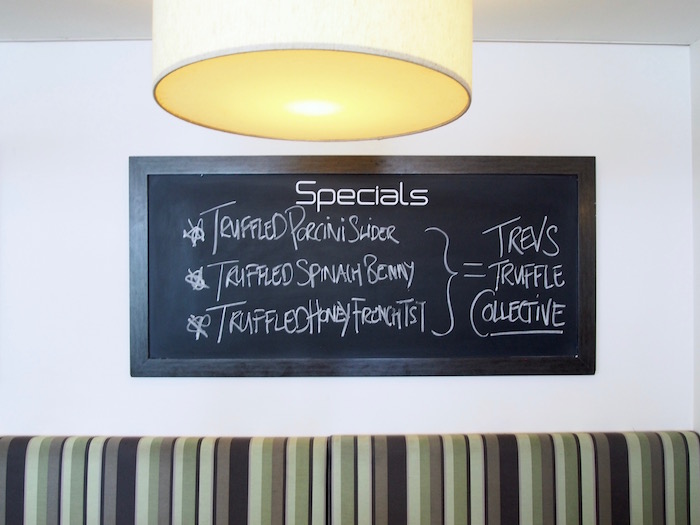 Blackboard menu that reads: Specials - Truffled Pocini Slider, Truffled Spinach Benny, Truffled Honey French Toast = Trevs Truffle Collective