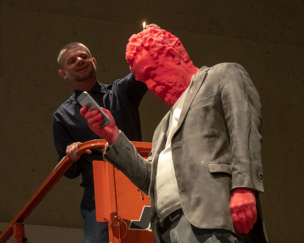 Nick Mitzevich, gallery director, gives life to 'Francesco' as he lights the sculpture